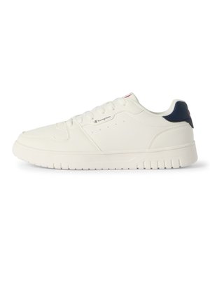 Witte lage sneaker met veters aan de voorkant, een marineblauwe hieltab en een klein Champion-logo aan de zijkant, getoond in zijaanzicht op een witte achtergrond.