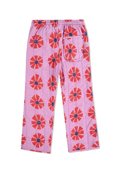 Pantalon en coton rose avec un motif floral répétitif en rouge et bleu marine, doté d'une taille élastique et d'une poche arrière unique.