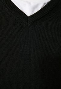 Pull noir en tricot avec un col en V, tissu texturé et détails côtelés au niveau du col et de l'ourlet. Couleur lisse et uniforme.