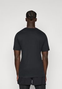 Schwarz meliertes T-Shirt mit kurzen Ärmeln, aus glattem Stoff gefertigt, mit klassischem Rundhalsausschnitt und lässigem Schnitt, von hinten präsentiert.