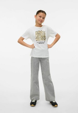 T-shirt en coton blanc avec un design imprimé de visages et le texte "AESTHETIC ART 2ND EDITION". Associé à un jean large gris clair et des baskets noires.