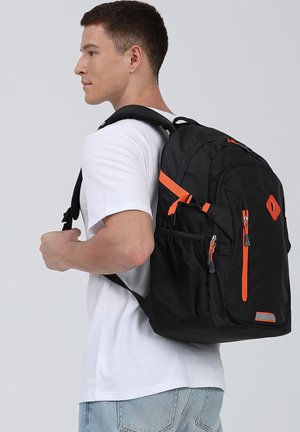 Zaino nero con accenti arancioni, dotato di tasche con zip, scomparti laterali in rete, spallacci regolabili e un design in tessuto testurizzato.