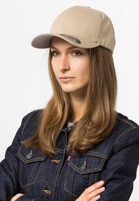 Cappellino da baseball beige realizzato in tessuto misto cotone, con visiera curva, cuciture a vista e un logo sul lato interno.