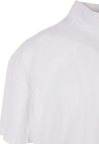 Hvit bomullspolo-shirt med ståkrage og korte ermer, med en glatt tekstur og enkelt design.