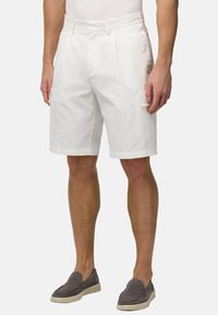 Shorts en coton blanc à coupe décontractée, avec un devant plat, des poches latérales et une poche cargo sur le côté droit.