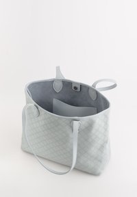 Lichtblauwe totebag met een gestructureerd hexagonaal patroon, van zacht leer, met een open bovenkant, dubbele handgrepen en een grijze suede binnenkant.