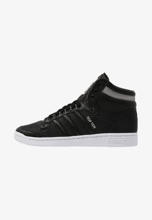 Baskets montantes noires Adidas avec semelle blanche, texte ""TOP TEN"" sur le côté, lacets noirs et bande réfléchissante près du col de la cheville.
