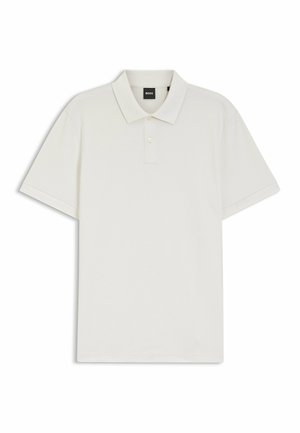 Polo blanco hecho de tela texturizada, con cuello puntiagudo, tapeta de tres botones y mangas cortas. Etiqueta de la marca visible.