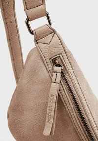 Bolso de cuero beige con superficie texturizada, forma angular, correa de hombro ajustable y cierre con un tirador decorativo de cuero.