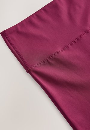 Tela deportiva burdeos con textura suave, que presenta costuras flatlock y un ajuste ceñido. Adecuada para ropa deportiva.