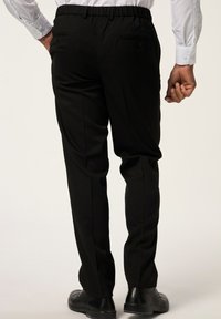 Pantaloni neri con vita elasticizzata, dotati di due tasche posteriori, con gamba dritta e una texture liscia. Abbinati a scarpe nere.
