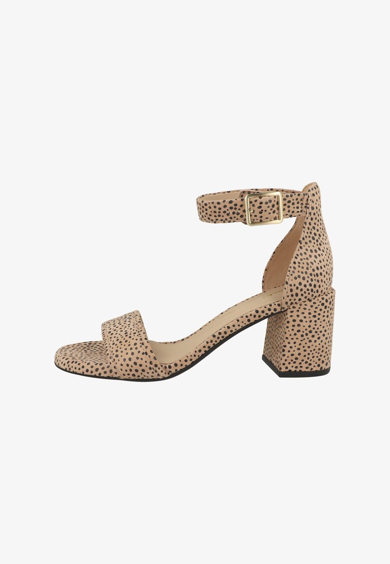 Beige sandaal met open teen, zwarte polka dots, blokhak en enkelbandje met gouden gesp, zijaanzicht op witte achtergrond.