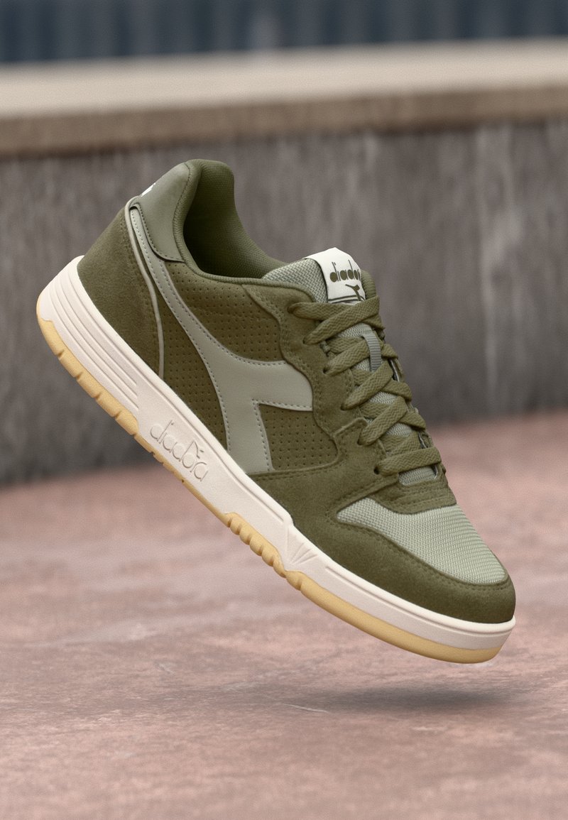 Baskets de sport vertes avec un mélange de daim texturé et de mesh respirant, présentant une semelle intercalaire blanche, un design à lacets et un accent de logo subtil.