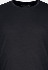 Schwarzes Rundhalsausschnitt-T-Shirt aus weichem Stoff. Hat eine glatte Textur mit minimal sichtbaren Nähten und einem einfachen Etikett im Halsbereich.