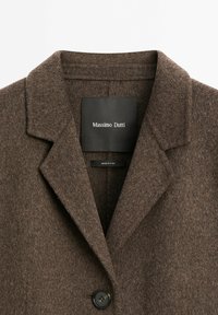 Brown wool coat with a notched collar, single button closure, and black interior label displaying "Massimo Dutti." Textured fabric.
