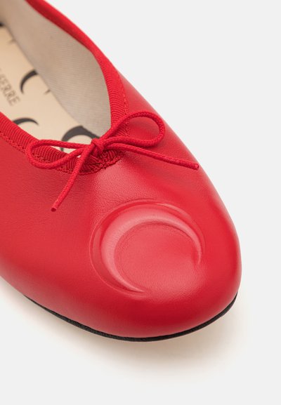 Red leather ballet flat with a rounded, textured toe cap and a matching bow. Features a smooth surface and a classic silhouette.