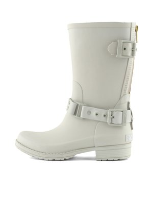 Botte en caoutchouc blanche avec un bout arrondi, une fermeture éclair latérale et une sangle ajustable. Présente une surface texturée et un petit talon bloc.