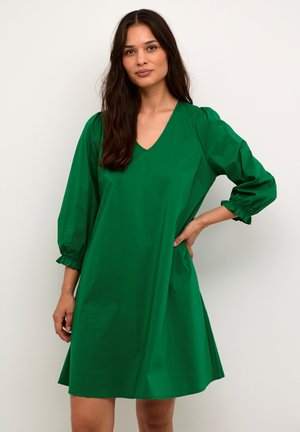Vestido corto verde de manga corta con escote en V, mangas abullonadas y puños fruncidos. Confeccionado en una tela suave y con una silueta simple.