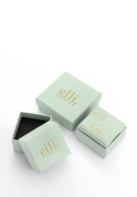 Cadeaux de couleur vert menthe avec une finition mate. Logo et texte dorés sur les surfaces. Une boîte est ouverte, révélant un intérieur noir.