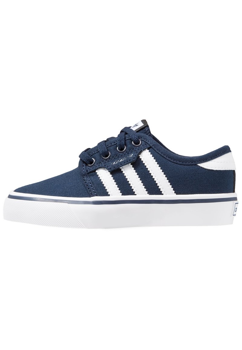 Canvas sneakers i marinblått med vita ränder och accenter. Platt vit gummisula, rund tå och ögla för snörning.