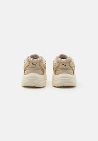 Beige running shoes with mesh and synthetic leather upper, textured design, cushioned sole, and trademark logo on the back.