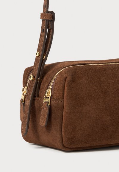 Braune Wildlederhandtasche in rechteckiger Form, mit goldenen Reißverschlussdetails und einem abnehmbaren Riemen. Glatte Textur mit subtiler Ausstrahlung.