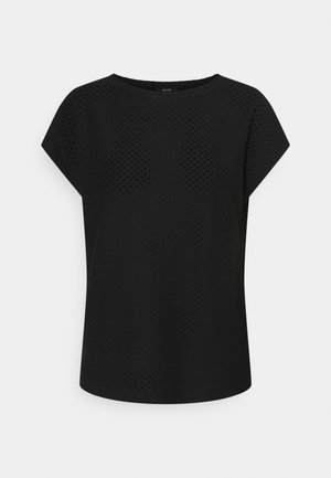 Blusa negra de manga corta con un sutil patrón perforado, cuello redondo y ajuste relajado sobre un fondo liso.