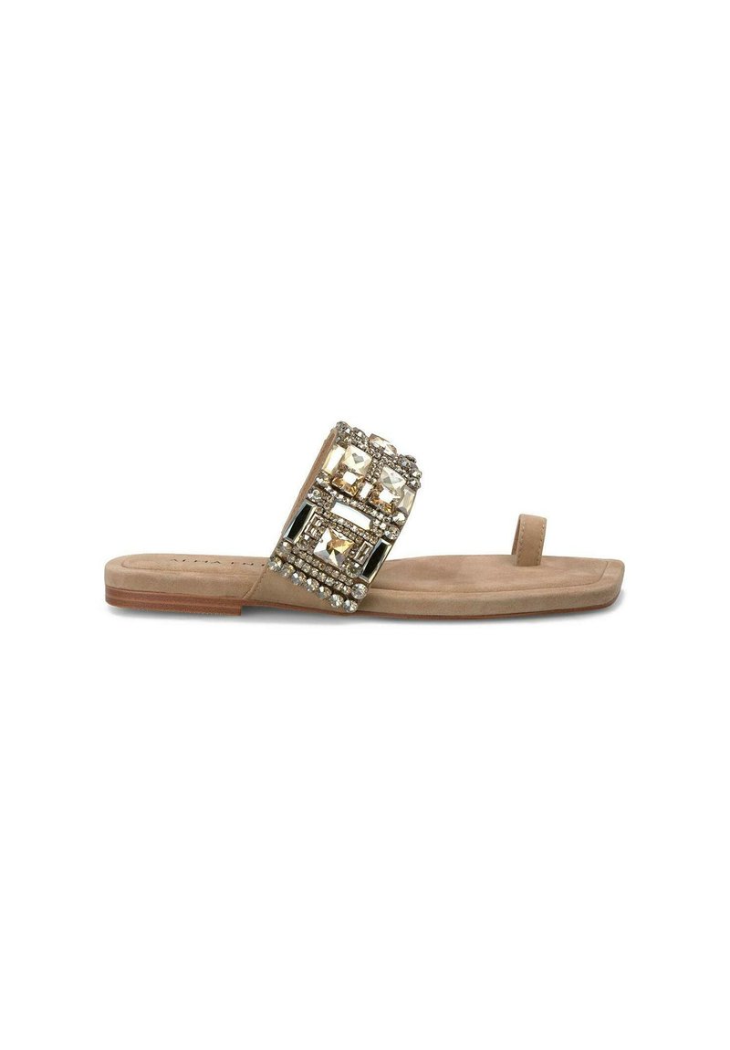 Sandalo piatto in pelle scamosciata beige con una larga fascia decorata con pietre geometriche trasparenti e dorate, caratterizzato da un anello per le dita e una suola piatta.