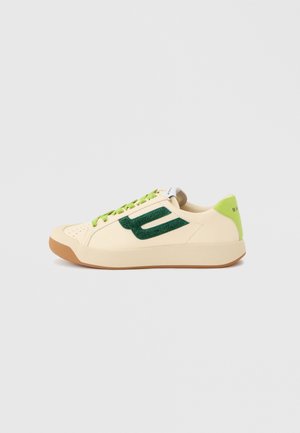 Sneaker beige low-top con logo "B" in suede verde, lacci verdi, linguetta posteriore verde chiaro e suola color gomma su uno sfondo semplice.