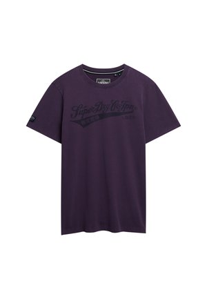 Lilla bomulds t-shirt med korte ærmer og rund halsudskæring. Har sort grafisk tryktekst over brystet og et lille logo på ærmet.