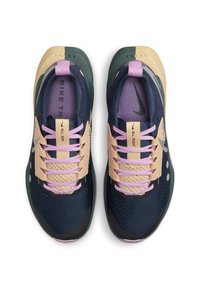 Zapatillas deportivas en azul marino y beige con acentos morados. Presenta una parte superior de malla, sistema de cordones y suela texturizada. Branding mínimo en la lengüeta y el costado.