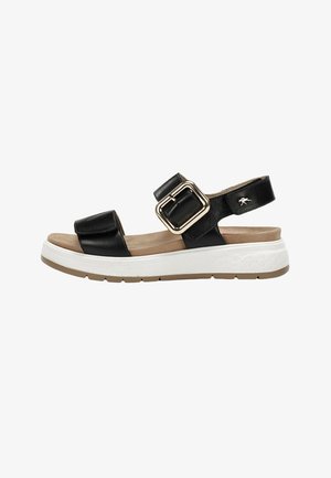 Sandalia de cuero negra con plantilla beige acolchada, tiras anchas ajustables, hebilla grande dorada y suela gruesa de goma blanca con banda de rodadura color canela.