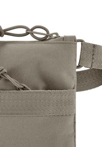 Borsa in tessuto grigia con superficie texturizzata, dotata di apertura superiore, hardware a loop e attacco per tracolla sul lato.