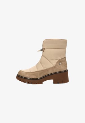 Botín beige hasta el tobillo con diseño acolchado, material de ante y sintético, suela marrón gruesa, cremallera lateral y costuras decorativas.