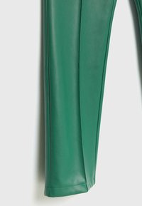 Jambe de pantalon en cuir synthétique vert avec coutures visibles et texture lisse sur un fond clair.