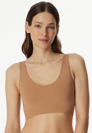 Light brown sports bra with a scoop neckline and wide straps, made from a smooth, stretchy fabric. Features a fitted, seamless design.