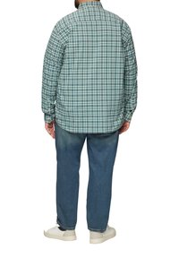 Langarm geruite blouse in blauw en wit, met een klassieke kraag, knoopmansjetten en een losse pasvorm, gecombineerd met blauwe denim jeans en witte schoenen.