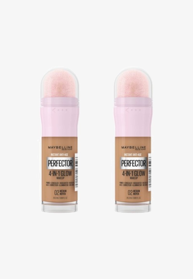 Maquillage Perfecting 4-en-1 Glow de Maybelline dans deux tubes identiques, avec des bouchons roses, des dessus transparents et une teinte caramel moyen.