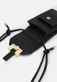 Czarna skórzana torba z zamknięciem na złotym elemencie. Posiada smukły design, regulowane sznurki oraz wewnętrzne kieszonki na przechowywanie.