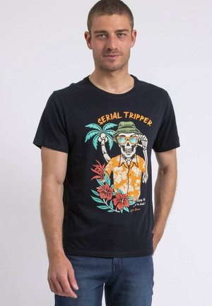 T-shirt en coton noir avec un graphique de squelette coloré portant une chemise hawaïenne orange, entouré de palmiers et de fleurs tropicales.