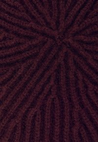 Tessuto lavorato a maglia bordeaux con un motivo texturizzato a coste che crea un effetto a spirale. Aspetto morbido e peloso con una profonda variazione di colore.