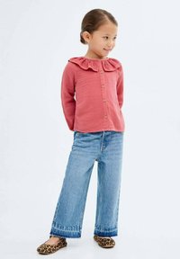 Cămașă de culoare ruginie cu guler volănaș și butoane, asortată cu blugi cu picioare largi de culoare albastră și pantofi fără toc cu imprimeu leopard. Textură netedă pe toată suprafața.