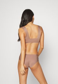 Brązowy zestaw bikini z teksturowanym stanikiem na szerokich ramiączkach i gładkimi, wysokim stanem dołem, obie części w jednolitym, ziemistym odcieniu.