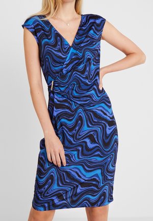 Robe-cache-coeur à motifs bleu et noir avec des manches courtes, présentant des lignes ondulées et un côté froncé avec un accent en bois. Tissu doux au toucher.