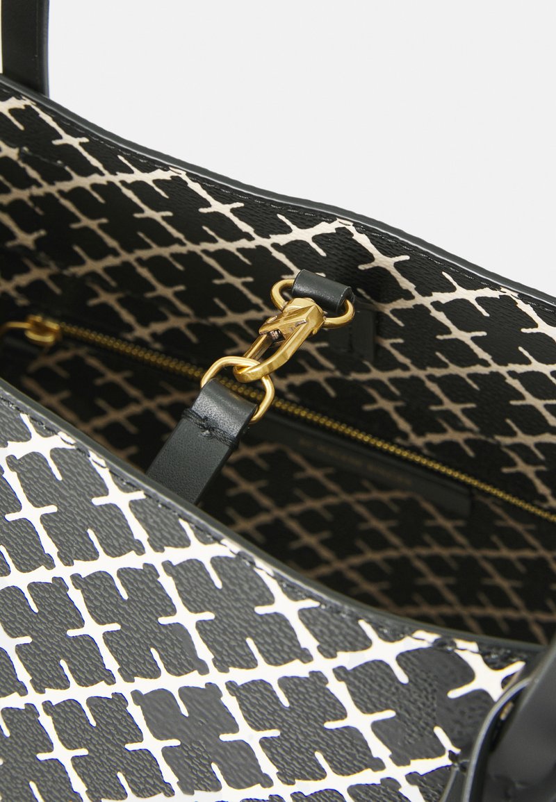 Svart och cream-färgad handväska med en geometrisk mönstring, texturerad yta, guldfärgad hårdvara och en ficka med dragkedja inuti.