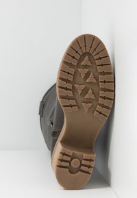 Hnědý kožený bot s texturovaným svrškem, vybavený gumovou podrážkou s trojúhelníkovým vzorem a bočním zipem.