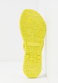 Bright yellow sandal sole showing textured rope-like pattern and size details US 7, EUR 37, UK 4 on a white background.