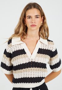 Dzianinowy sweter polo z krótkim rękawem i dekoltem w kształcie litery V, z naprzemiennymi paskami w kolorze czarnym, beżowym i białym; teksturowany otwarty splot.