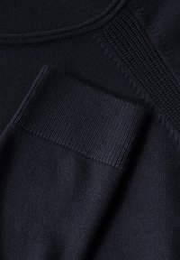 Dunkelblauer Strickpullover mit glatter Textur und geripptem Bündchen, das ein dezentes gewebtes Muster an der Schulternaht aufweist.