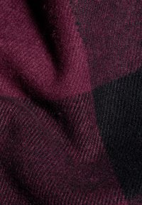 Tessuto scozzese in profonde tonalità di bordeaux e nero. Materiale in lana morbida e strutturata con un aspetto caldo e accogliente e un motivo a quadri distintivo.